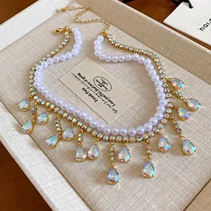 Macro view of an elegant double-layered necklace featuring pearls and crystal teardrop tassels.