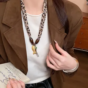 Primo piano di una collana in tessuto leopardato con perle di legno e ciondolo pesce
