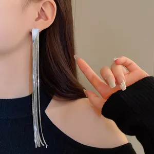 Close-up of long silver tassel earrings worn with minimalist aesthetic style