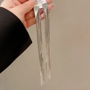 Detailed view of long silver tassel earrings held by hand showcasing elegant drape