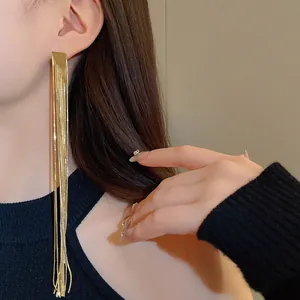 Elegant long gold plated tassel earrings worn by a female model in black top.