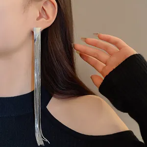 Detail of long silver tassel earrings with a sleek minimalist triangle stud design