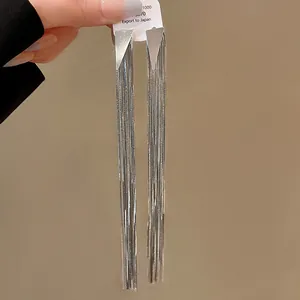 Detail view of long silver tassel earrings with geometric triangle stud