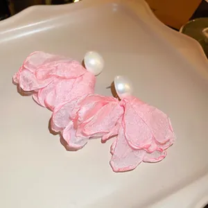 Primer plano detallado de pendientes con pétalos de flores de tela rosa y gran perla blanca