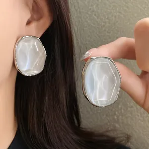 Detailed macro view of pearlescent oval earrings with textured silver-toned borders