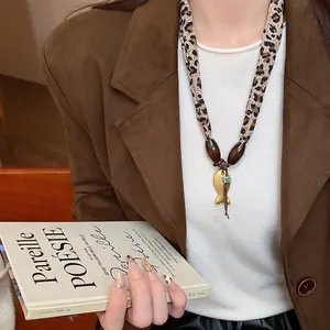 Elegante collana in tessuto leopardato con ciondolo a forma di pesce d'oro su una modella