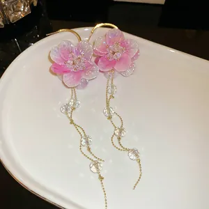 Vista detallada de pendientes de borlas con flores rosas y pétalos brillantes.