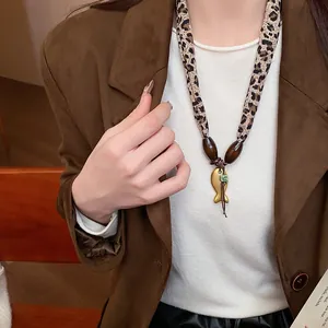 Primo piano di collana con ciondolo a pesce in ceramica, cordino leopardato e perle
