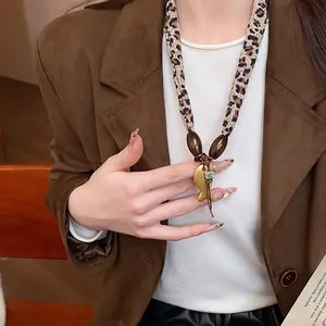Primo piano di una collana leopardata con perle in legno e piccolo ciondolo a pesce oro.