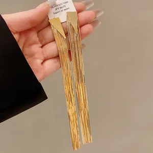 Close-up of gold-plated long tassel earrings with triangular studs shown on hand