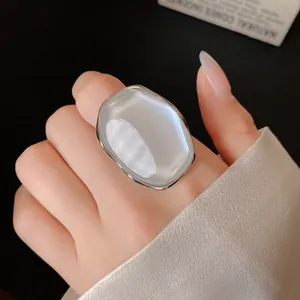 Close-up detail of a large pearlescent oval statement ring with a smooth silver-tone metal frame