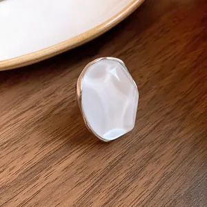 Detail shot of a minimalist pearlescent oval stud earring with an elegant silver-toned border