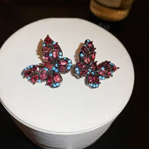 Dettaglio ravvicinato di orecchini vintage a farfalla con strass di cristallo rosso e blu