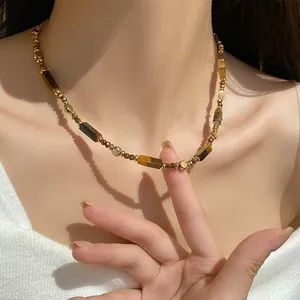 Detailaufnahme einer vergoldeten Perlenkette mit zylindrischen Tigeraugen-Steinen