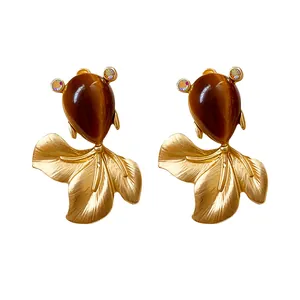Vintage gold fish earrings with brown teardrop stone and crystal eyes on white background