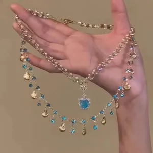Detailed view of a layered gold necklace featuring a blue heart crystal pendant