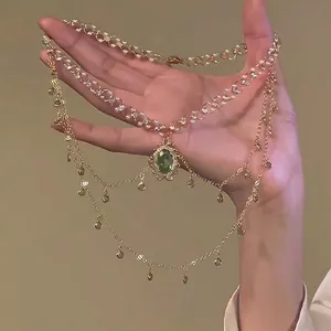 Detailed close-up view of a luxury layered gold necklace with a green gemstone pendant