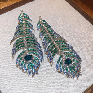 Vista macro di orecchini vintage a piuma di pavone con strass blu e verdi scintillanti