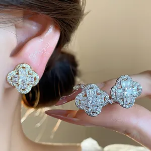 Close-up of zircon-encrusted four-leaf clover ear clips in gold and silver plating