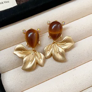 Close-up detail of vintage goldfish earrings with brown teardrop stones and textured gold fins