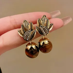 Close-up of vintage palace style earrings with leaf design and tiger eye beads.