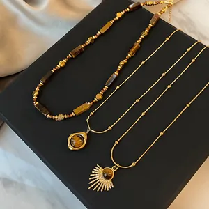 Detailansicht goldbeschichteter Halsketten mit Tigerauge-Perlen und Sonnenanhängern