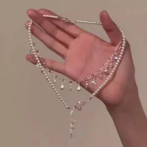 Macro detail of double-layered pearl necklace with pink butterfly crystal pendant
