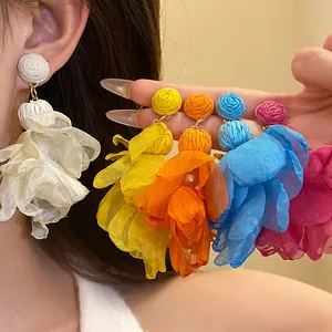 Dettaglio di orecchini a fiore in chiffon colorati con rafia per stile vacanziero