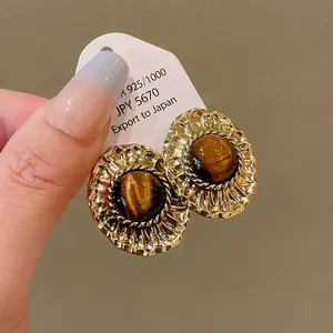 Close-up of retro gold earrings with tiger eye stone inlay