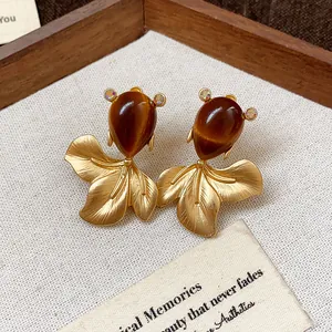Macro detail of vintage goldfish stud earrings featuring brown teardrop stones.