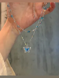 Close-up detail of an elegant double-layered necklace featuring a blue butterfly pendant