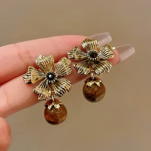 Close-up detail showing the vintage gold flower design and tiger eye stone bead of the earrings
