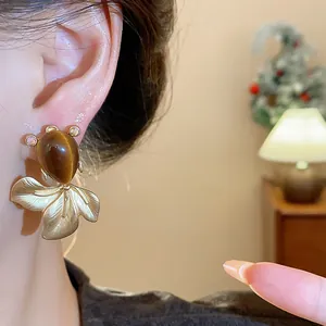 Detailed view of a vintage goldfish stud earring with brown cat eye stone worn on ear
