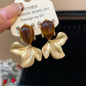 Close-up of vintage goldfish stud earrings with brown teardrop resin and gold finish