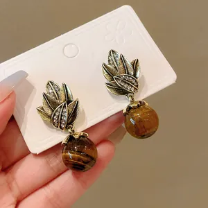 Detailed macro view of vintage gold leaf earrings with polished tiger eye stone beads