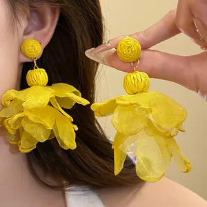 Vista dettagliata di orecchini pendenti con petali di fiori in rafia gialla e chiffon estivi
