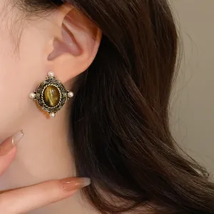 Detail shot of a vintage court style earring featuring a tiger's eye stone and pearls