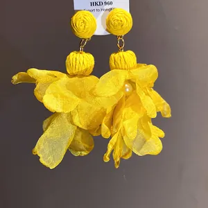 Dettaglio degli orecchini a fiore in chiffon giallo con rafia e perla decorativa
