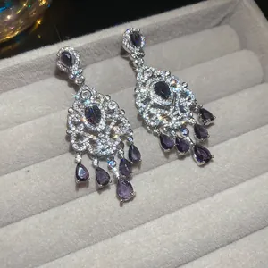 Dettaglio degli orecchini a fiore vintage con pietre a goccia viola e cristalli