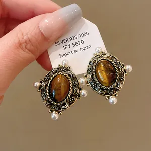 Detailed view of vintage palace style 925 silver earrings with tiger eye stone and pearls
