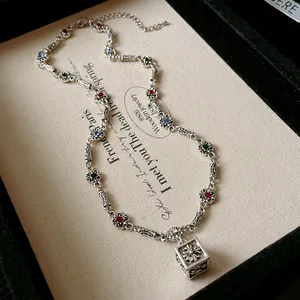Close-up detail of retro silver necklace with a square floral pendant and colorful stones