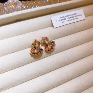 Primo piano dettagliato di orecchini vintage con strass colorati su un vassoio di velluto beige.