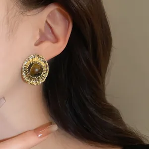 Detail view of vintage palace style oval earring featuring a central brown tiger's eye stone