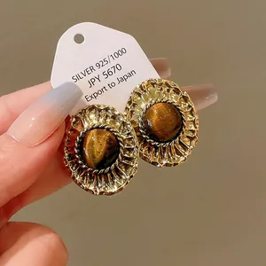 Macro view of vintage gold-plated palace style earrings with tiger eye stone