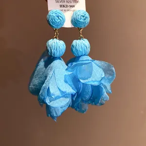Dettaglio di orecchini a fiore in chiffon blu con palline di rafia e argento