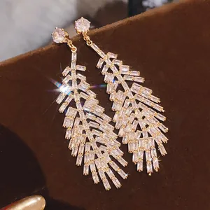 Dettaglio di orecchini pendenti a foglia d'oro vintage con cristalli baguette brillanti