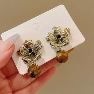 Macro view of vintage gold flower earrings featuring polished tiger eye stone drops.