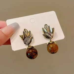 Close-up detail of vintage style tiger eye stone drop earrings with gold leaf design