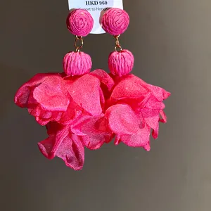 Dettaglio ravvicinato di orecchini a fiore in rafia e chiffon rosa