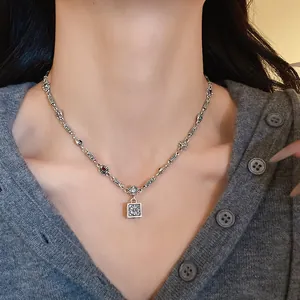 Close-up of a vintage silver-toned necklace featuring a square floral engraved pendant
